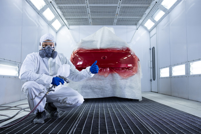 Fahrzeuglackierer vor einem frisch lackierten Auto