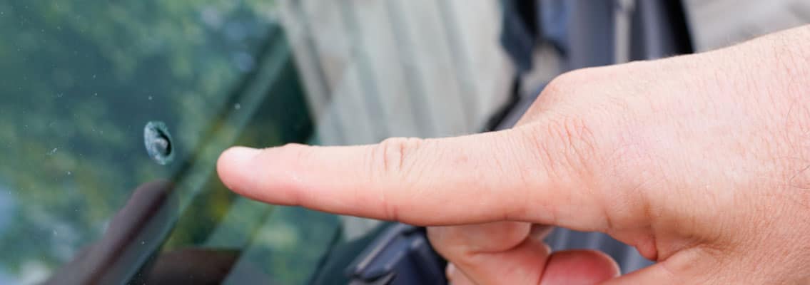 Hand zeigt auf Steinschlag in Frontscheibe