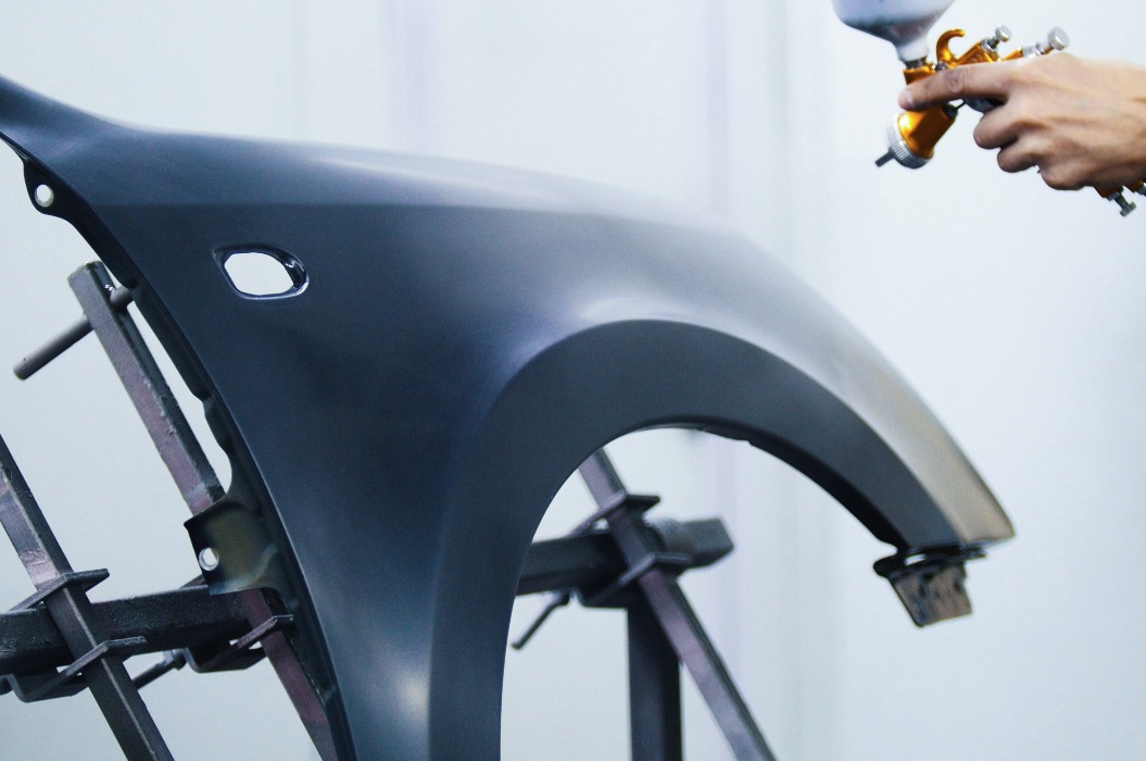 Professioneller Autolackierer lackiert in Garage mit Airbrush